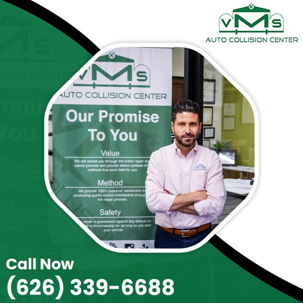 Auto collision shop manager standing with arms crossed in front of a VMS Auto Collision Center banner outlining customer promises for value, method, and safety.